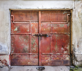 Metal padlock on a red metal old garage gates