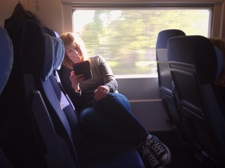 Frau liest Buch im Ebook Reader während Zugfahrt