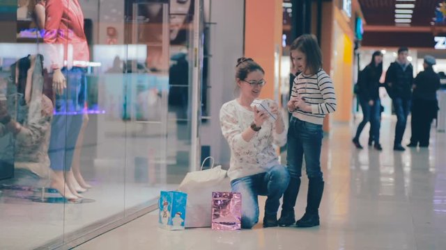 Mother shows her daughter a pesent, just baught in mall while shopping. HD.