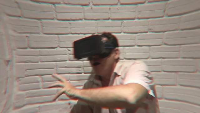 Man wearing virtual reality VR headset glasses fights imaginary creatures during an emotional simulated virtual adventure gaming session - he then swims in a virtual ocean.