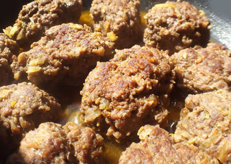 Frying large homemade meatballs on a pan