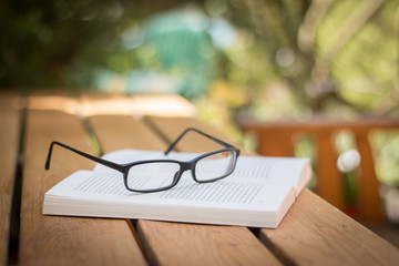 Buch und Brille auf Holztisch im Garten, Vignettierung