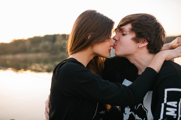 Happy couple hugging and kissing at sunset on the pier on a sunny summer day. Love concept