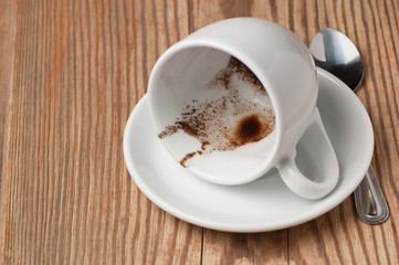 Drunk cup of coffee with coffee grounds on saucer on wooden table, low angle view with place for text