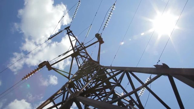 High voltage tower with sky background. High-voltage power line. A high voltage power pylons against blue sky and sun rays - Stock Video