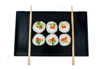 Sushi on a black wooden tray with chopsticks isolated on white background

