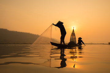 fisherman on boat with sunrise background, the Mekong River in Thailand.