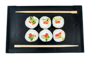 Sushi on a black wooden tray with chopsticks isolated on white background
