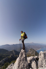 Young man with backpack on a mountain top on a sunny day.