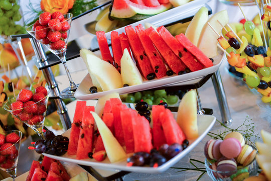 Plates with different type of fruits: grapes, strawberries, pineapple, watermelon, apricots