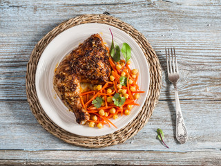 Grilled chicken and fresh carrots chickpea salad on a light wooden background.