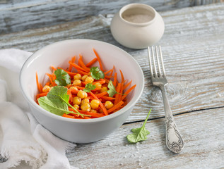 Fresh carrot and chickpea salad on a light wooden background. Delicious vegetarian food
