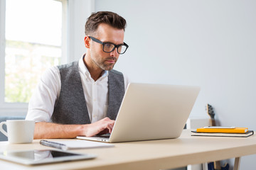 Mid adult man working on laptop from home