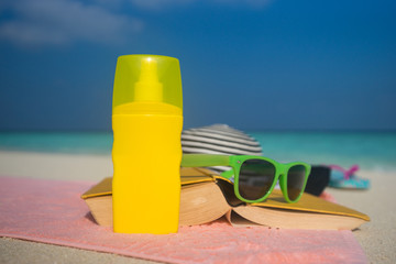 Sunscreen, hat and sunglasses on tropical beach