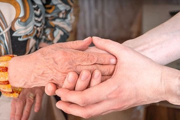 Man holds hands of eldery woman. Senior help concept.