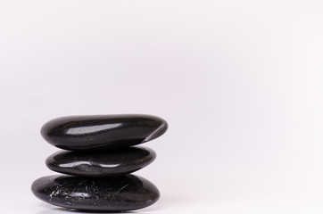 Fototapeta na wymiar Stone treatment. Black massaging stones isolated on a white background. Hot stones. Balance. Zen like concepts. Basalt stones.