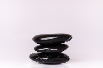 Stone treatment. Black massaging stones isolated on a white background. Hot stones. Balance. Zen like concepts. Basalt stones.