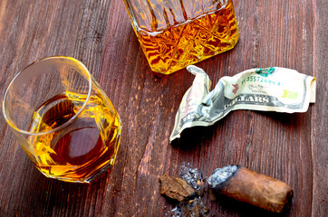 Whisky in a glass with a cigar, money, and a carafe of vintage