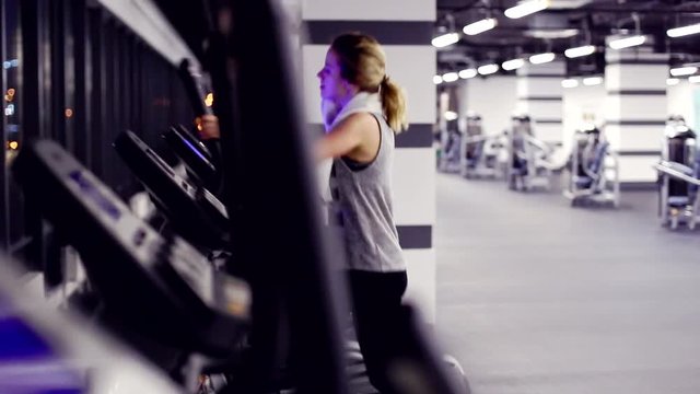 view of emty gym with one girl on elliptical trainer. Workout on elliptical trainer 