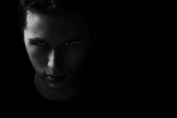 dark young adult man portrait fade in black background