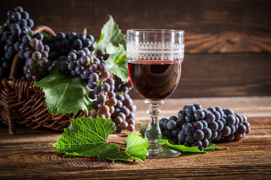 Tasty red wine with grapes in wicker basket