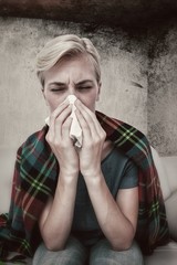 Composite image of sick blonde woman blowing her nose 