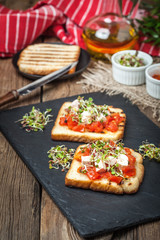 Grilled toasted bread with roasted tomatoes, feta cheese and radish sprouts.