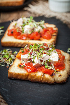 Grilled toasted bread with roasted tomatoes, feta cheese and radish sprouts.