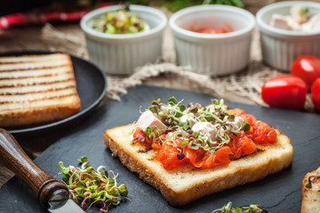 Grilled toasted bread with roasted tomatoes, feta cheese and radish sprouts.