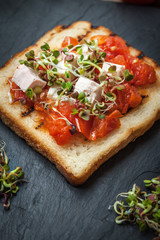 Grilled toasted bread with roasted tomatoes, feta cheese and radish sprouts.