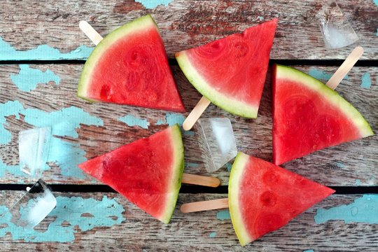 Group of watermelon slice popsicles on a rustic blue wood background