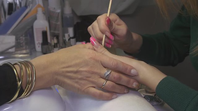 Professional manicurist put off shellac cover from nails of woman in beauty saloon by orange stick, shake powder puff. Close up