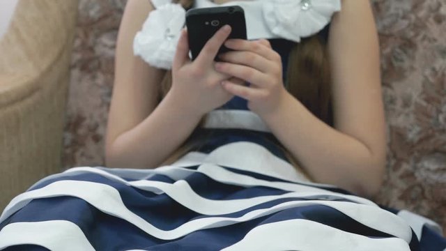 Little girl holds a smartphone and plays the game