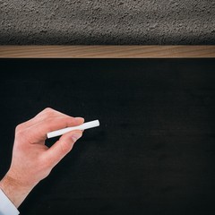 Composite image of businessman writing with white chalk 