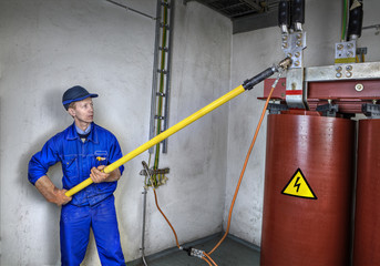 Electrician engineer uses insulating rod to earth grounding transformer.