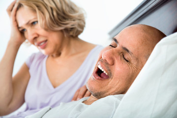 Mature tired girl looking at snoring boyfriend