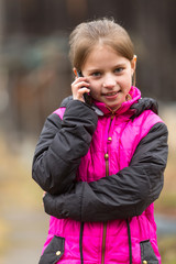Fototapeta premium Funny little girl talking on the phone, outdoors portrait.