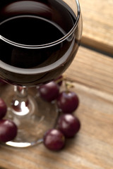 wine with red grapes on wooden surface