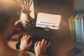 New life chapter one against young woman using typewriter