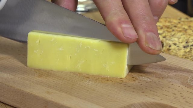 Slow motion of slicing white cheddar cheese
