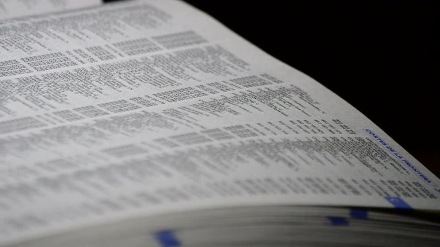 Page of phone book with names and address rotating in a black background