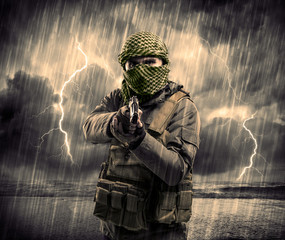 Dangerous armed terrorist with mask and gun in a thunderstorm wi