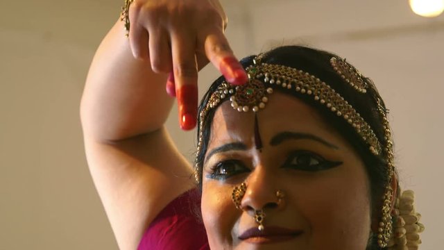 A lovely young woman in traditional dance costume performing classical Indian dance movements.