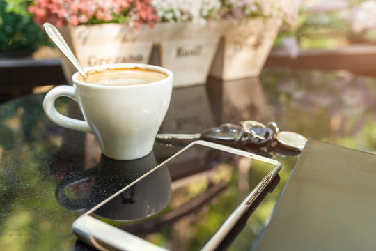 Digital smartphone and cup of coffee on desk with vintage flower