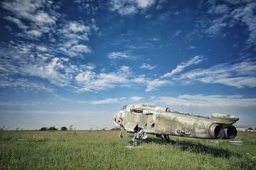 An abandoned fighter jet on a field.