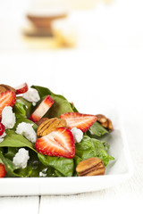 cropped image of spinach salad with strawberry slices and pecan nuts