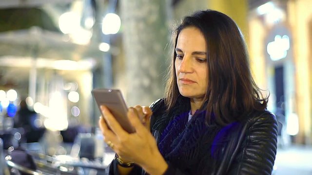 Woman browsing internet on smartphone in the cafe at night, steadycam shot
