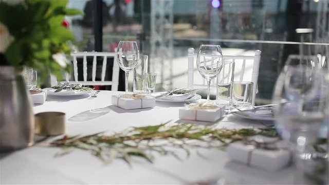 Glasses on white cloth table served for lunch or dinner in luxurious outdoor terrace restaurant with cozy interior
