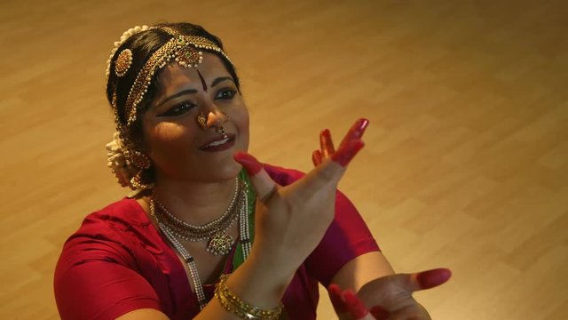 The painted fingers and adornment of bangles  and bracelets accent the hand gestures of a traditional Indian dancer.