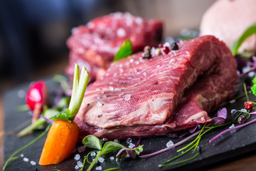 Steak.Beef steak.Meat.Portioned meat.Raw fresh meat.Sirloin steak.T-Bone steak. Flank steak. Duck breast. Vegetable decoration. Portioned meat prepared for processing in a restaurant or hotel kitchen.